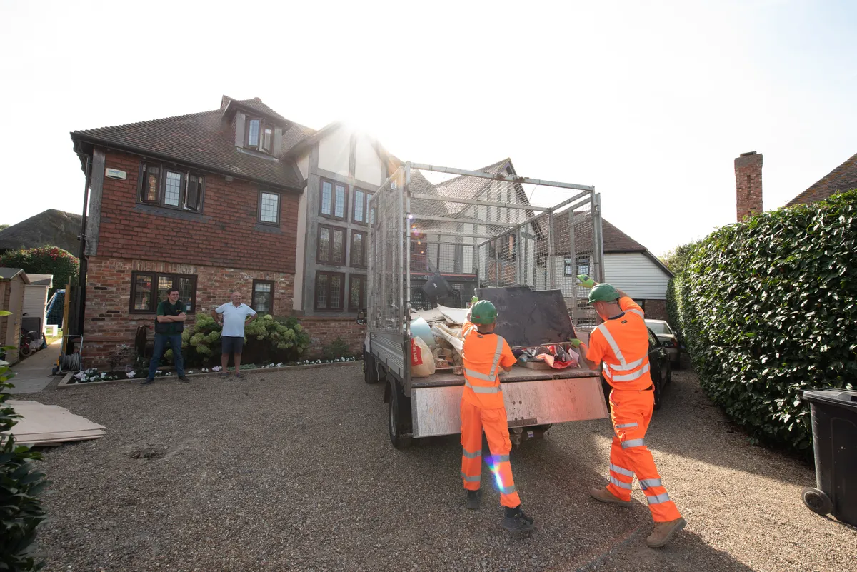 Two men loading a television on their truck during our rubbish removal service